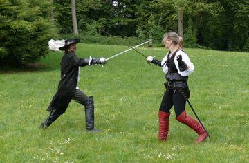 Ein Fechtpaar bei Stich und Parade vor einem Schloss
