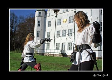 Zwei Fechter im Duell vor einem Schloss
